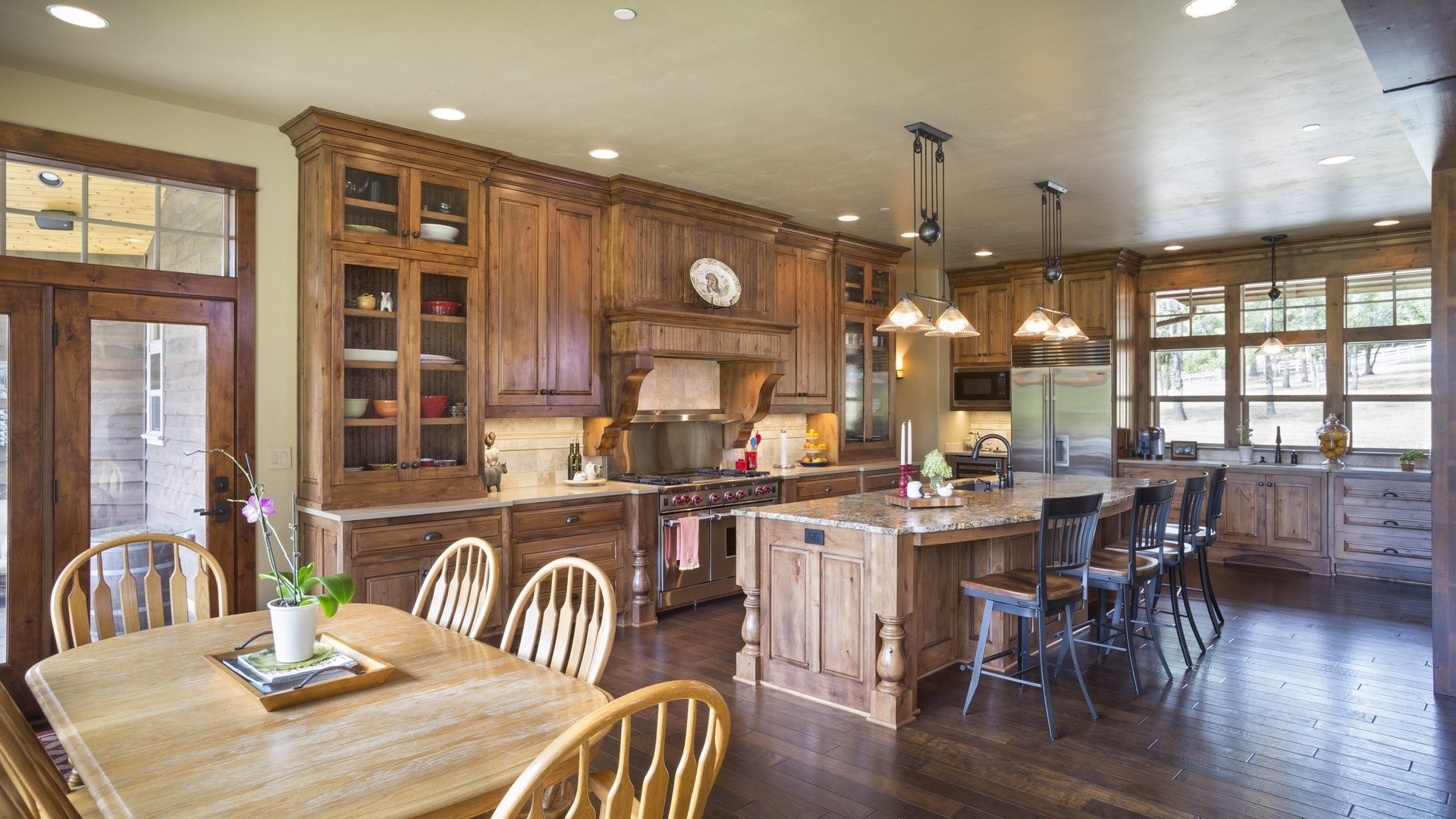 HD PC desktop wallpaper showcasing a spacious kitchen with wooden furniture, modern cabinetry, and a large island under warm lighting in a well-designed room.