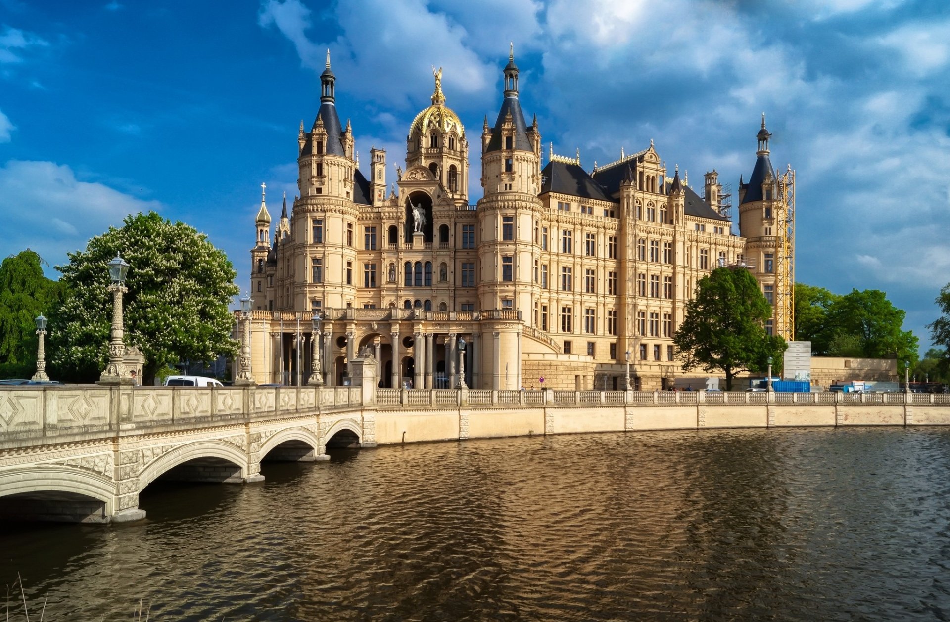HD PC desktop wallpaper of Schwerin Palace, a majestic man-made castle reflected in the water under a vibrant blue sky.