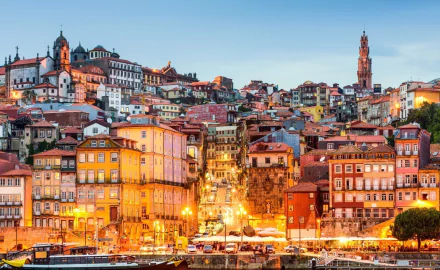 HD desktop wallpaper showcasing the colorful, densely packed man-made buildings of Porto illuminated at dusk under a clear sky.