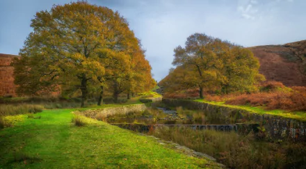 HD PC desktop wallpaper and background: nature river scene with a calm stream winding between autumn trees and grassy banks under a pale blue sky.
