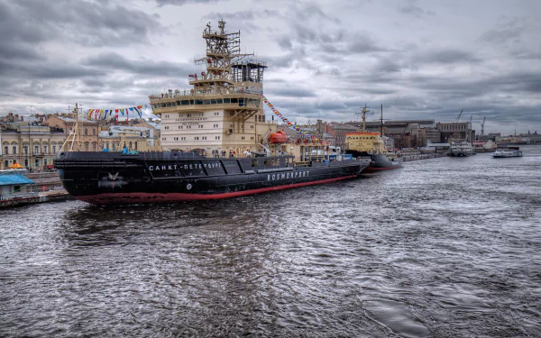 HD desktop wallpaper featuring an icebreaker vehicle navigating a cloudy waterfront, showcasing the vessel’s robust design against an overcast sky.