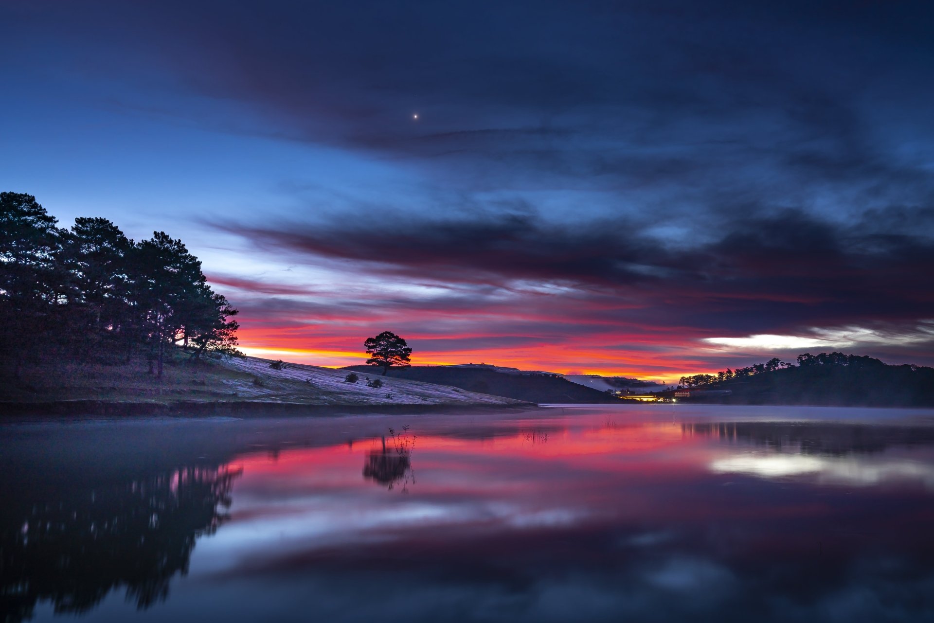 8K Ultra HD desktop wallpaper featuring a serene lake at sunset with vivid clouds and their reflection, surrounded by silhouetted trees in a tranquil natural setting.