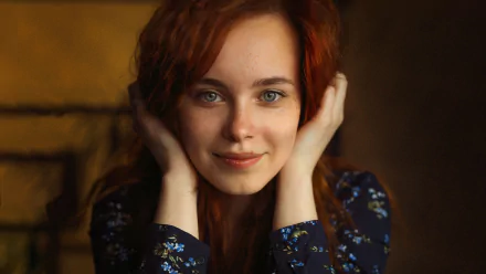 Close-up of a redhead woman model with blue eyes, gently holding her face, featured in an HD PC desktop wallpaper background.