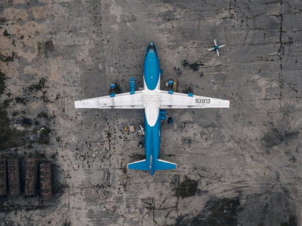 Aerial view of a blue and white military Antonov An-12 aircraft on a concrete tarmac, captured in HD for a desktop wallpaper and background.
