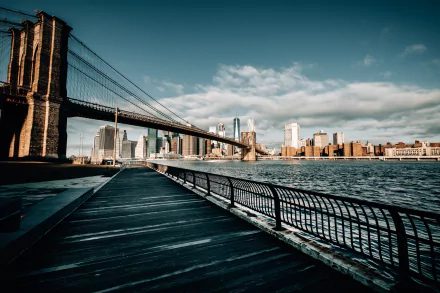 HD desktop wallpaper of the Brooklyn Bridge spanning the East River with the New York City skyline in the background under a partly cloudy sky.