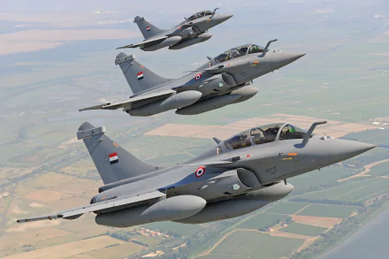 Three Dassault Rafale jet fighter warplanes flying in formation over a landscape, captured in a high-definition military aircraft wallpaper.