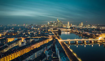 Aerial night view of Frankfurt, Germany — illuminated bridges and riverside buildings reflecting city lights on the river; man-made skyline HD desktop wallpaper background.