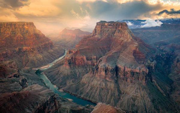 HD desktop wallpaper capturing the Colorado River winding through the majestic cliffs and vast landscape of the Grand Canyon at sunset.