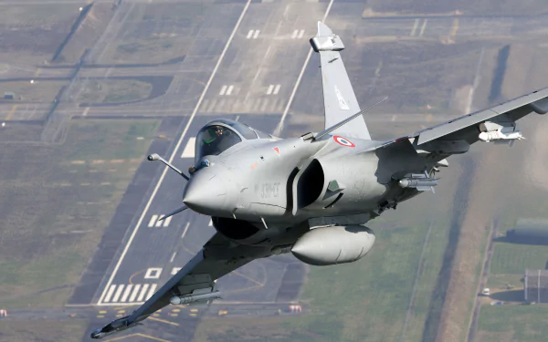 HD desktop wallpaper featuring a Dassault Rafale jet fighter warplane flying low over an airstrip, showcasing its sleek military aircraft design.