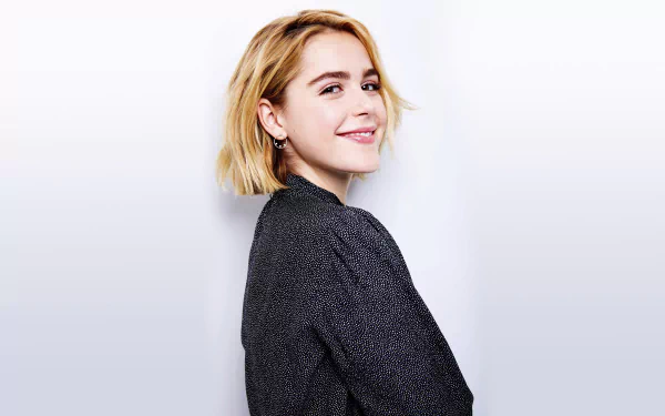 Smiling American actress Kiernan Shipka with short blonde hair poses against a plain white background in this 8K Ultra HD desktop wallpaper.