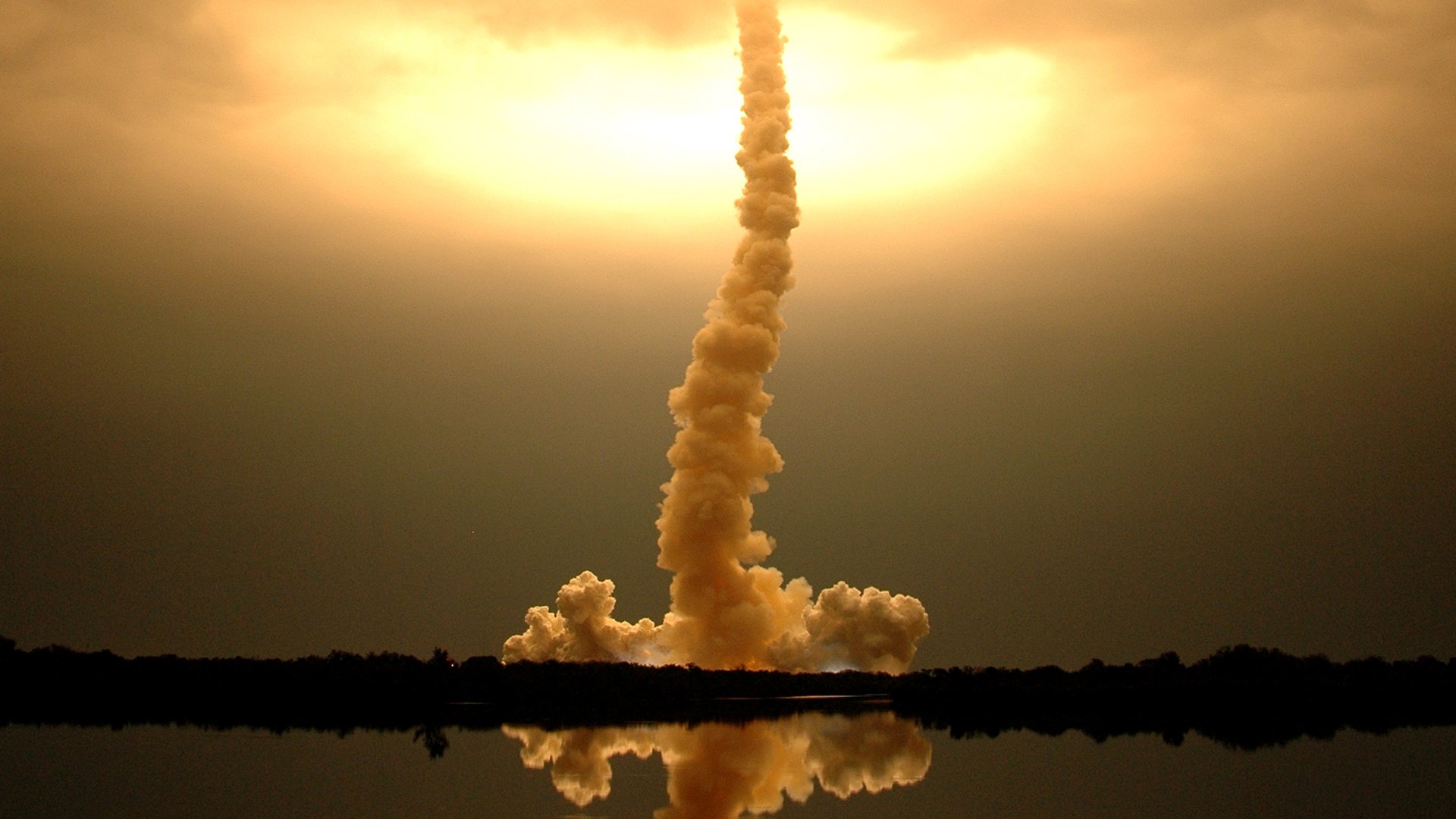 A man-made NASA rocket launch captured at sunset, with smoke and flame reflected in the water below, featured as an HD PC desktop wallpaper and background.