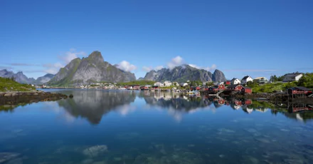 Scenic view of the Lofoten Islands in Norway showcasing a tranquil river reflecting rugged mountains and colorful houses, captured in stunning 4K Ultra HD quality.