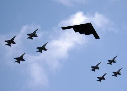 A stunning HD desktop wallpaper featuring a formation of McDonnell Douglas F/A-18 Hornets flying alongside the Northrop Grumman B-2 Spirit during a military air show.