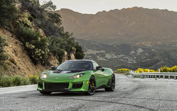 A green Lotus Evora GT grand tourer supercar parked on a mountain road at sunset, captured in 4K Ultra HD for a PC desktop wallpaper background.