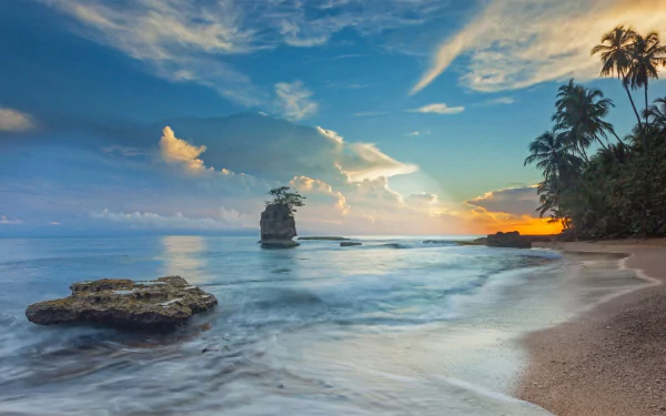 HD desktop wallpaper of a tropical Costa Rica beach at sunset, featuring the ocean, sky, horizon, and palm trees along the shore.