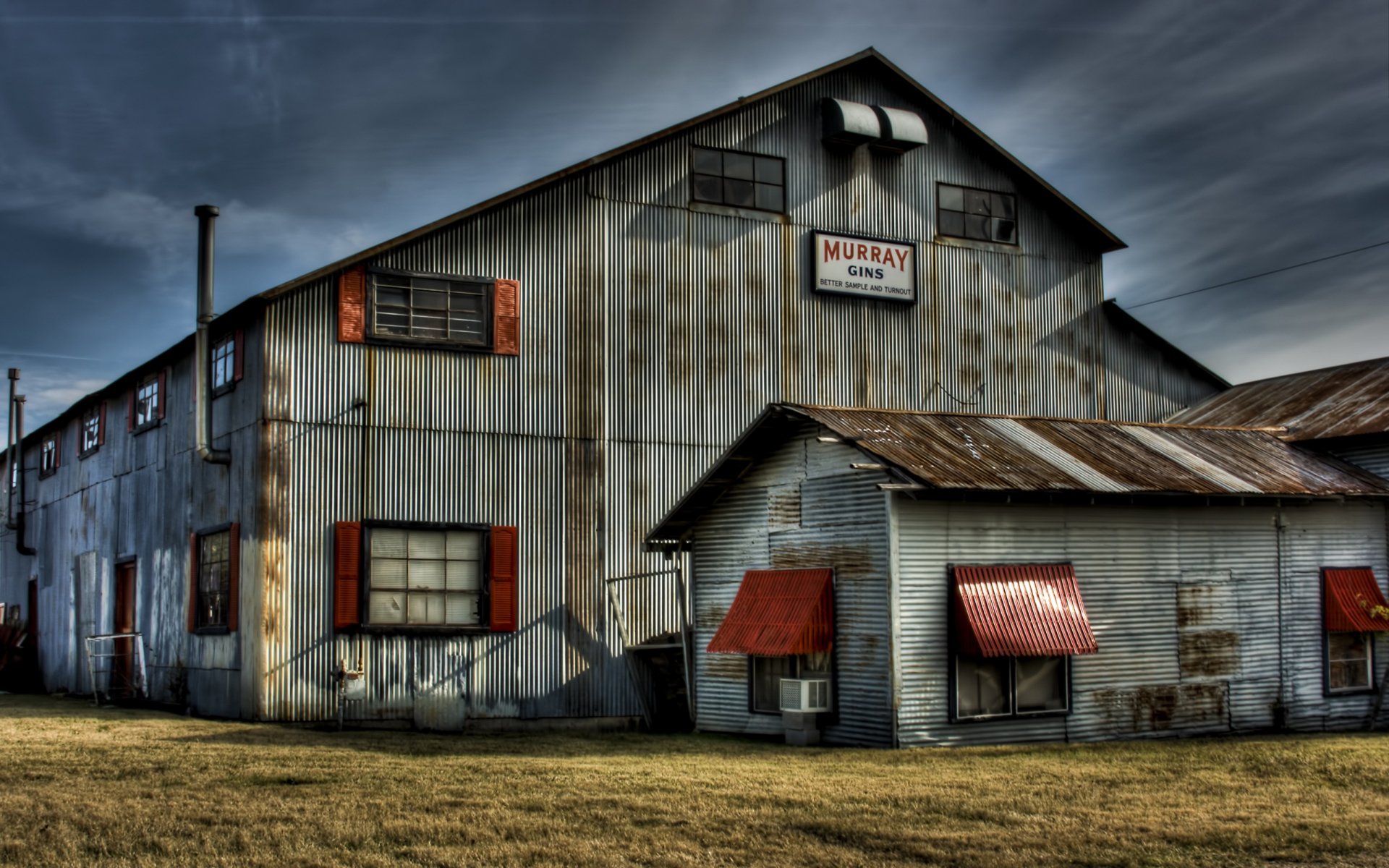 Abandoned HDR man-made industrial building with rusted metal siding and red awnings beneath a moody sky — 2K Quad HD PC desktop wallpaper/background.