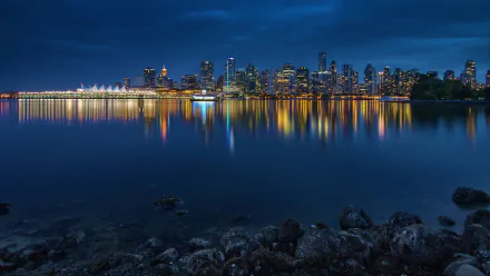 Nighttime panorama of Vancouver's illuminated skyline reflecting on calm water, showcasing the man-made beauty of this Canadian city in 4K Ultra HD clarity.