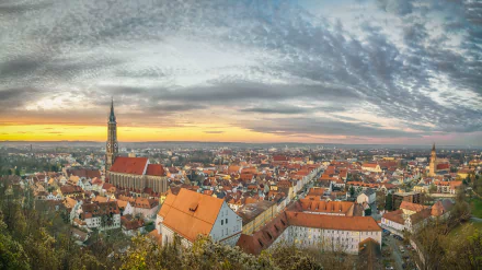 Panoramic view of a man-made Bavarian town in Germany at sunset, featuring historic buildings and a dramatic cloudy sky in this HD desktop wallpaper.