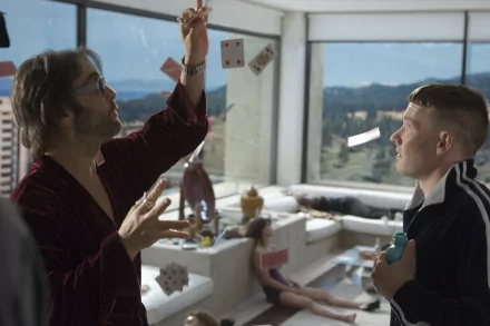 A scene from the movie Smokin' Aces featuring Joel Edgerton and Jeremy Piven, showcasing a dramatic moment amidst chaotic surroundings with cards and characters in a stylish setting.