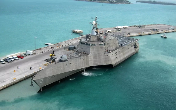 The USS Independence (LCS-2) is a littoral combat ship docked at a pier, showcasing its modern military design against a vibrant turquoise sea.