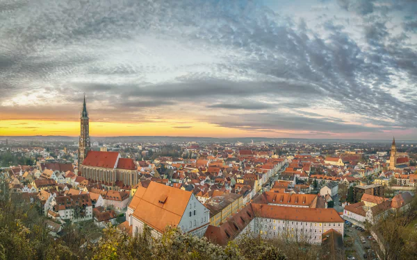 Panoramic view of a man-made Bavarian town in Germany at sunset, featuring historic buildings and a dramatic cloudy sky in this HD desktop wallpaper.