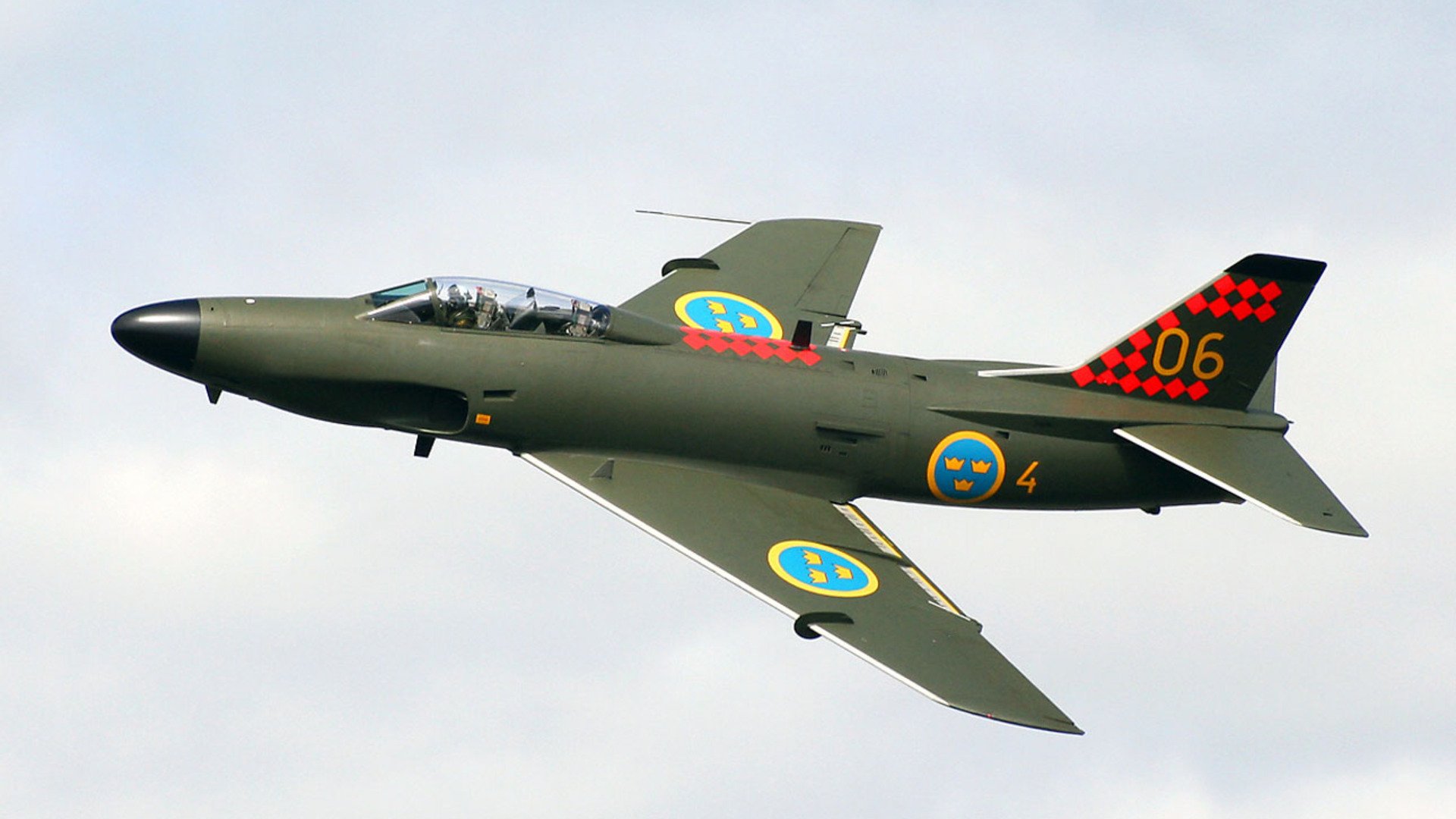 HD desktop wallpaper showing a Swedish Air Force military aircraft in flight against a cloudy sky.