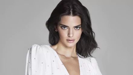 HD desktop wallpaper portrait of a dark-haired model with brown eyes and an intense stare, wearing a white blouse against a neutral gray background.