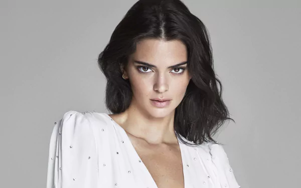HD desktop wallpaper portrait of a dark-haired model with brown eyes and an intense stare, wearing a white blouse against a neutral gray background.