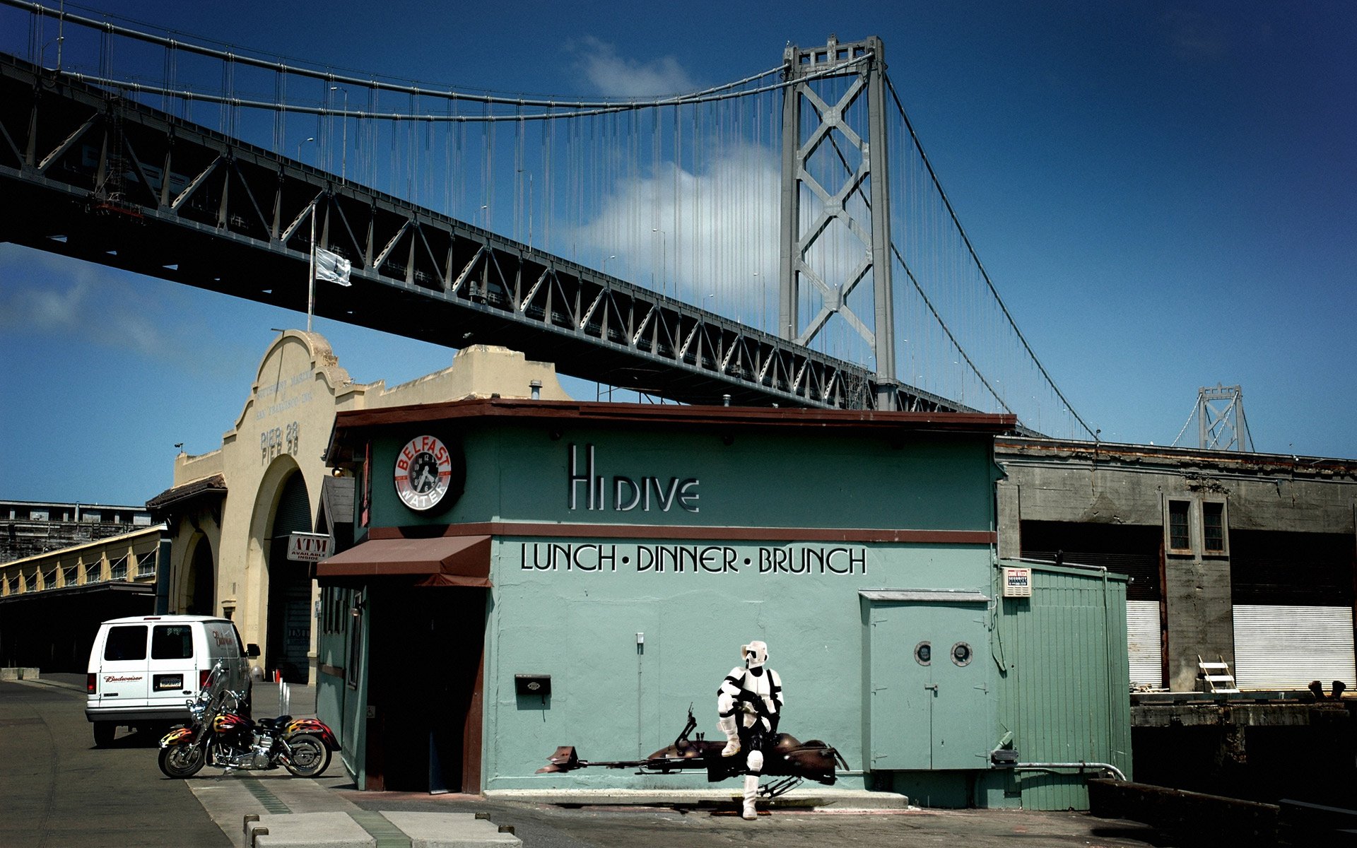 HD PC desktop wallpaper showing a Scout Trooper from Star Wars sitting humorously outside a corner diner with a bridge overhead, blending sci-fi and urban life.