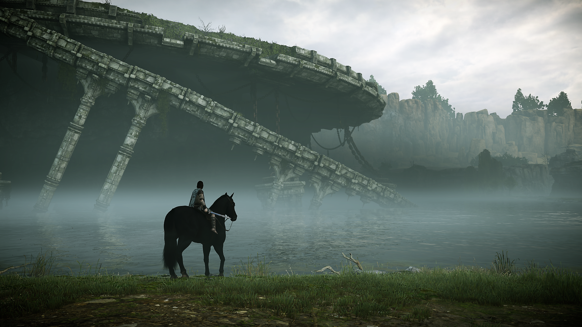 Shadow of the Colossus (2018) HD PC desktop wallpaper: lone rider on horseback by misty water beneath a vast ruined colossus structure and distant cliffs.