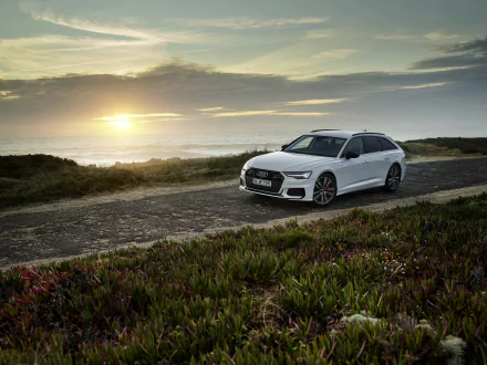 White Audi A6 Avant station wagon on a coastal road at sunset with ocean horizon — 4K Ultra HD PC desktop wallpaper background.