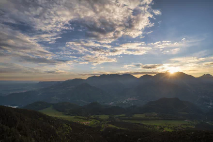 Sunrise casts golden sunbeams over a mountainous landscape under a vibrant sky, captured in stunning 8K Ultra HD photography for a vivid desktop wallpaper.