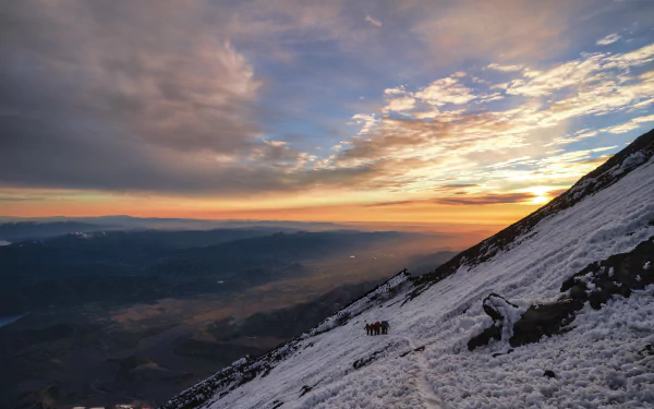 A group of mountaineers climb a snowy slope at sunset in this 8K Ultra HD winter sports desktop wallpaper.