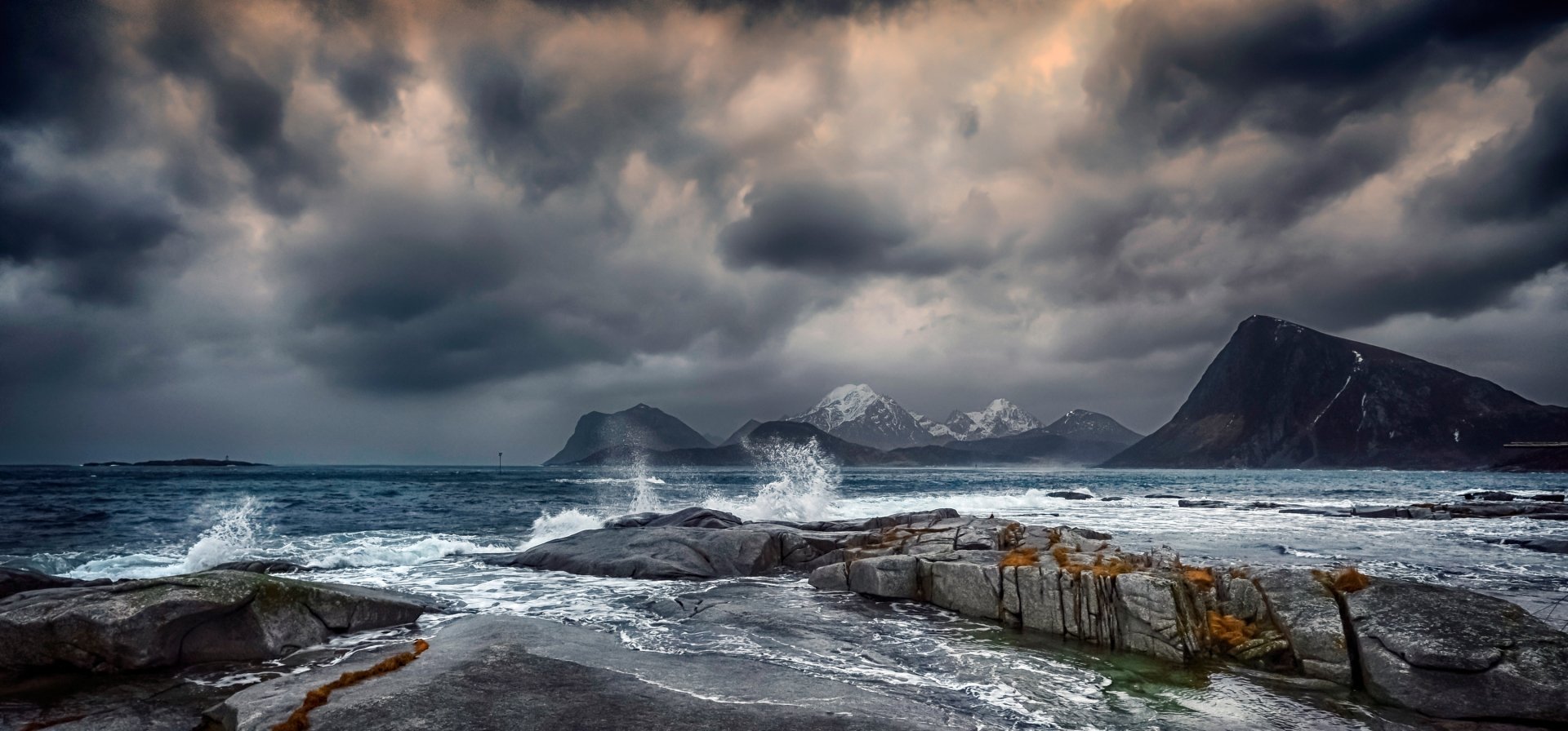 2K Quad HD PC desktop wallpaper/background: moody Lofoten coast, Norway — low clouds over jagged mountains, churning sea and wave-swept rocky foreground (photography).