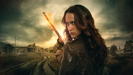 HD desktop wallpaper featuring Melanie Scrofano as Wynonna Earp, holding a glowing gun against a moody, desolate town backdrop from the TV show Wynonna Earp.