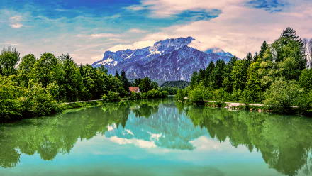 HD PC desktop wallpaper featuring vibrant greenery and a serene lake reflecting rugged mountains under a partly cloudy sky, capturing the beauty of nature.