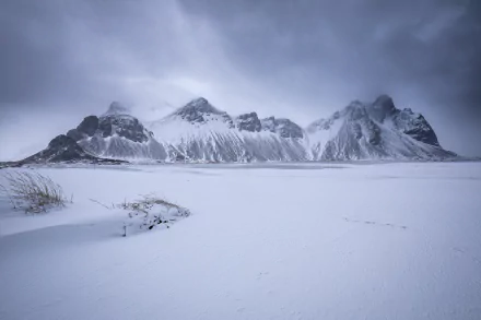 Snow-covered Vestrahorn Mountain in Iceland under a cloudy sky, captured in stunning 4K Ultra HD as a nature desktop wallpaper background.