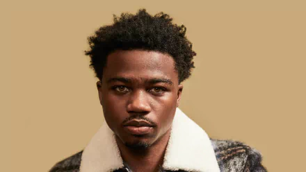 HD wallpaper featuring Roddy Ricch, showcasing his distinct hairstyle and serious expression against a neutral background, embodying the essence of contemporary music.