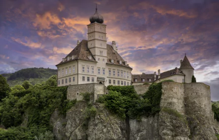 Schloss Schönbühel, a historic man-made castle perched on a cliff in Hungary, captured in stunning 4K Ultra HD against a dramatic sunset sky.