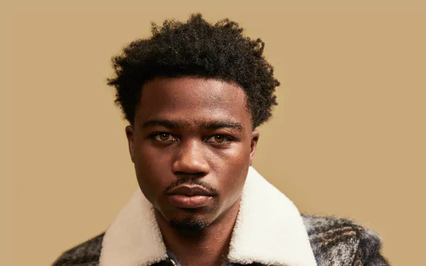 HD wallpaper featuring Roddy Ricch, showcasing his distinct hairstyle and serious expression against a neutral background, embodying the essence of contemporary music.