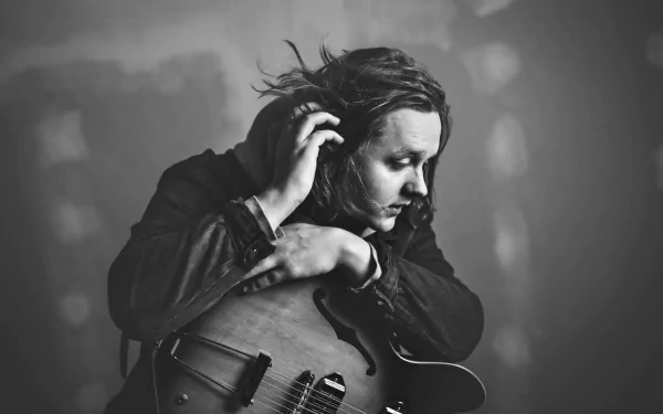 Monochrome HD wallpaper featuring a pensive musician with a guitar, providing a creative and moody desktop background atmosphere.