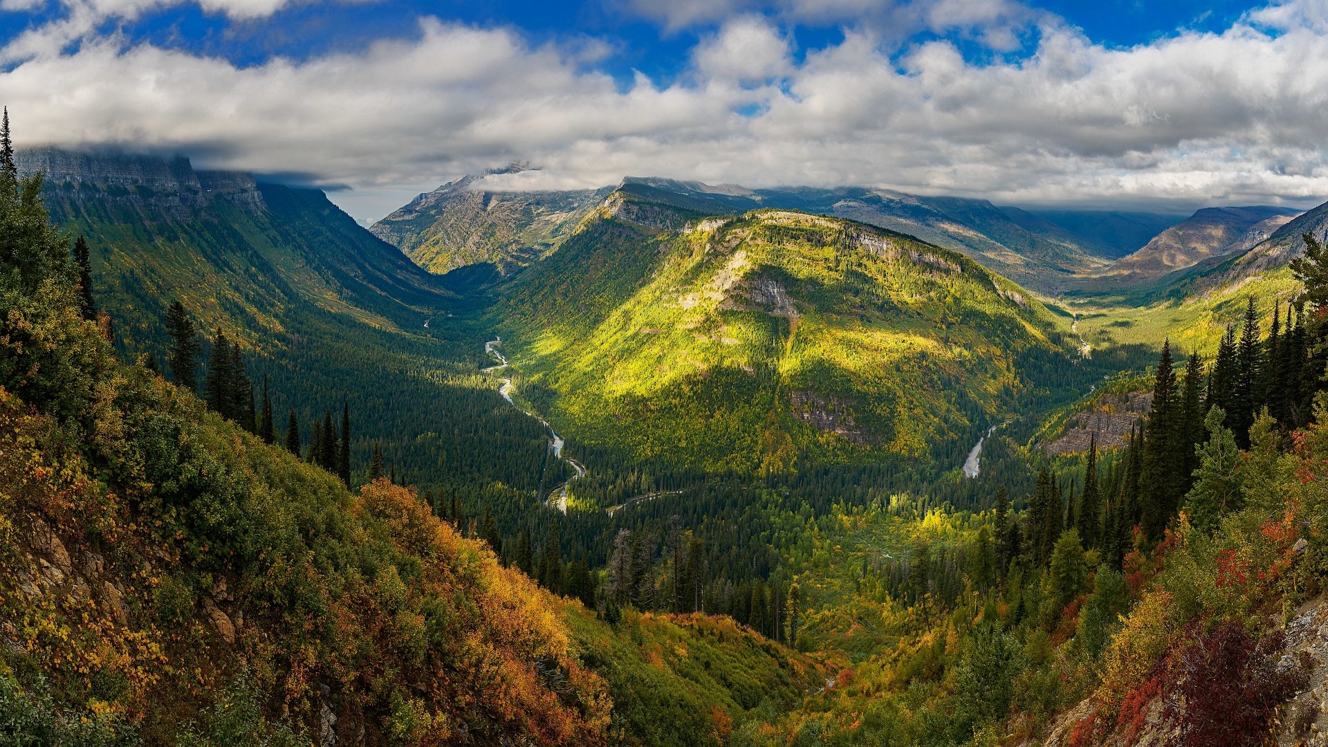 A vibrant 4K Ultra HD desktop wallpaper showcasing a lush forest and rugged mountain landscape under a dramatic sky.