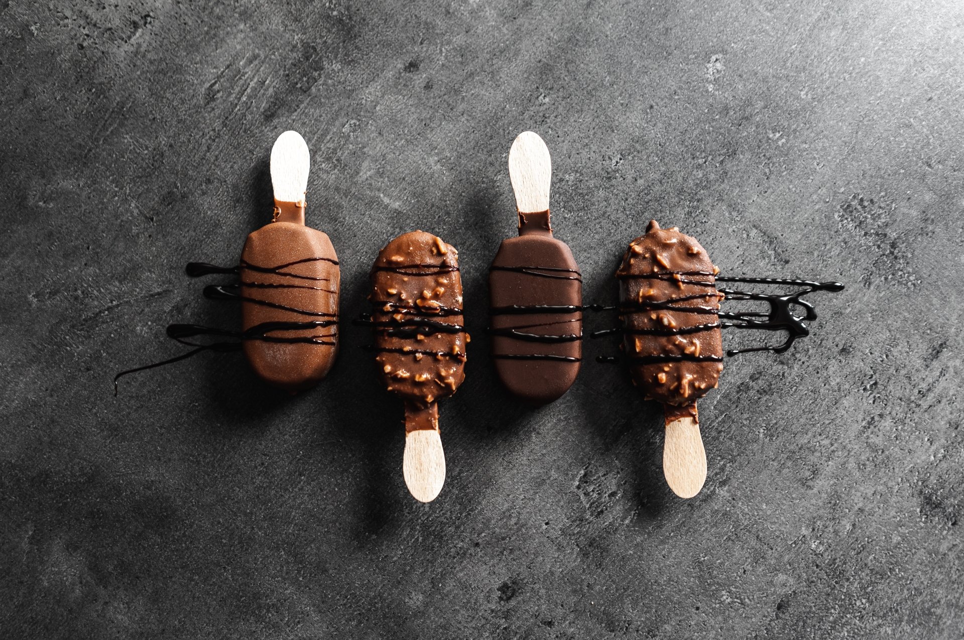5K Ultra HD PC desktop wallpaper: four chocolate-covered ice cream bars drizzled with dark chocolate on a textured dark background — chocolate food ice cream