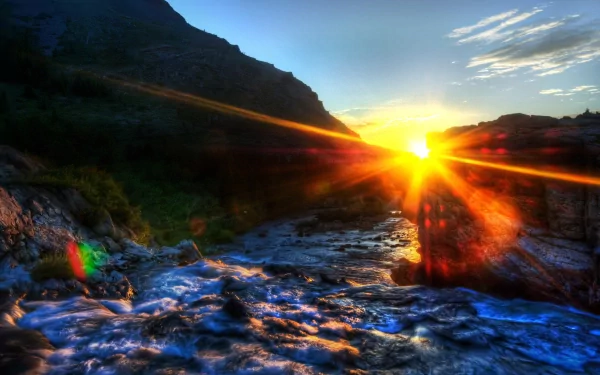 4K Ultra HD nature wallpaper capturing a vibrant sunset over a flowing stream surrounded by rugged hills and a partly cloudy sky.