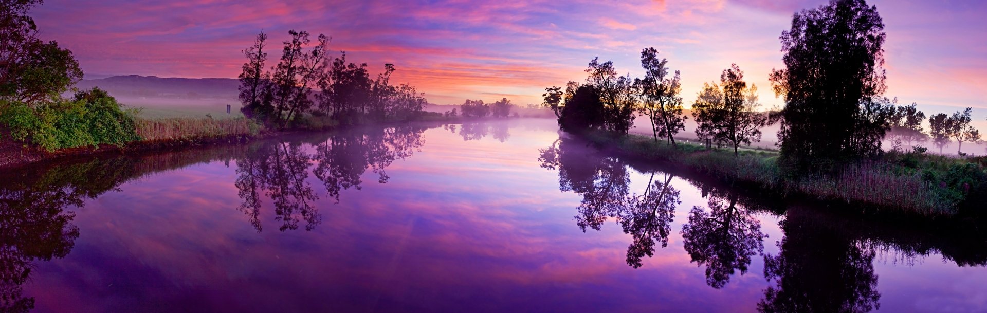A serene 4K Ultra HD desktop wallpaper showcasing a calm river at dawn with vibrant clouds, fog, and nature reflected in the still water under a colorful sky.