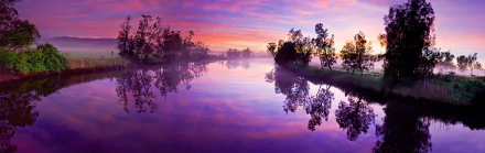 A serene 4K Ultra HD desktop wallpaper showcasing a calm river at dawn with vibrant clouds, fog, and nature reflected in the still water under a colorful sky.
