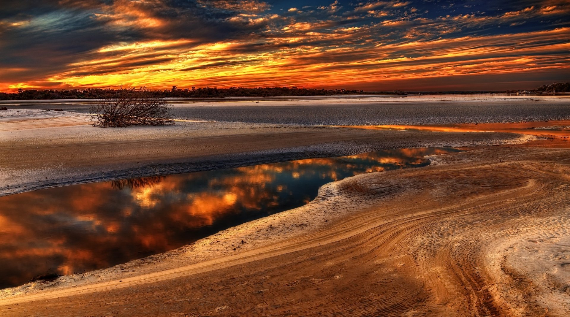 Florida sunset over sandy tidal flats, fiery clouds mirrored in calm reflection pools — vibrant nature scene, 2K Quad HD PC desktop wallpaper/background.
