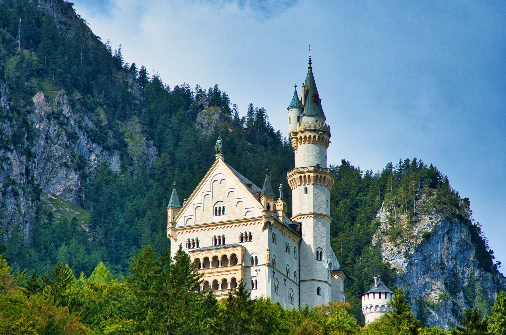 4K Ultra HD image of Neuschwanstein Castle, a man-made historic landmark nestled among forested mountains in Germany.