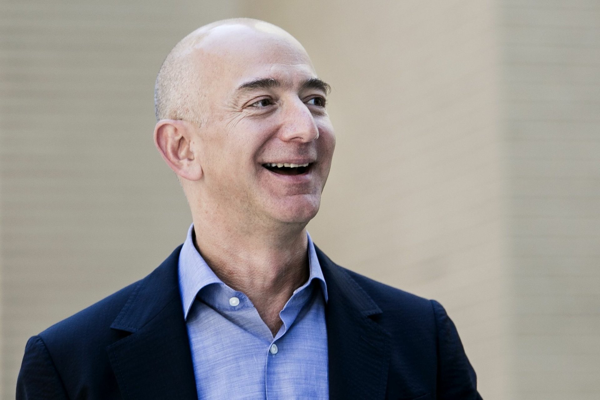 HD desktop wallpaper featuring a smiling man in a suit, set against a subdued background.