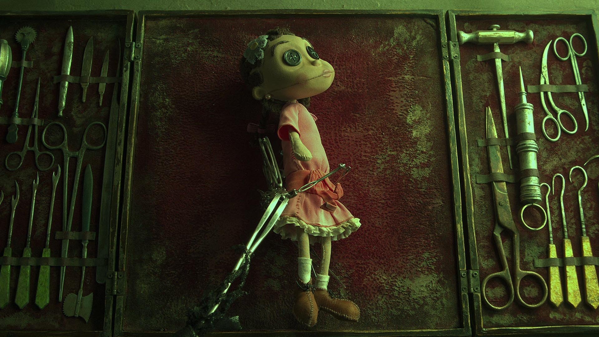 HD PC desktop wallpaper: eerie scene from the movie Coraline — a button-eyed doll bound to a bloodstained board flanked by surgical tools.